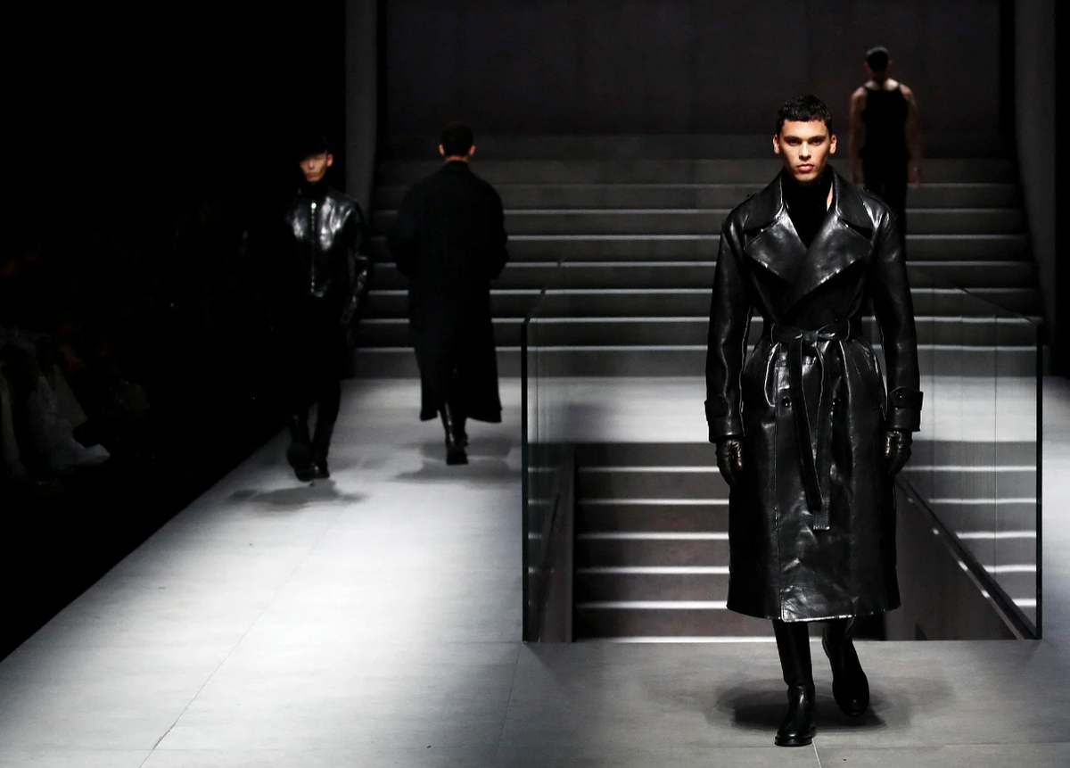 Model op de catwalk in een zwarte leren trenchcoat